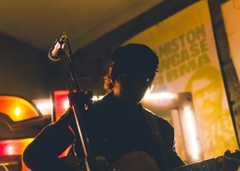 man playing guitar near corded microphone