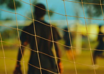 man in black T-shirt through soccer goal post