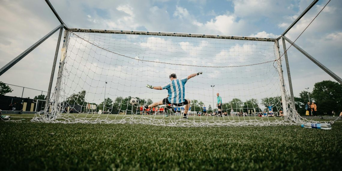 boy in blue shirt playing soccer during daytime