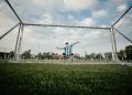boy in blue shirt playing soccer during daytime