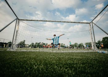 boy in blue shirt playing soccer during daytime