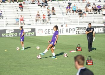 two woman standing on green soccer field