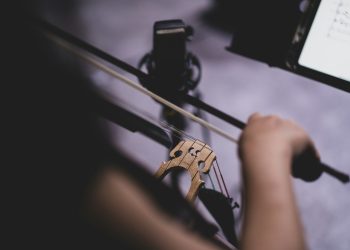 a person holding a violin string and a cell phone