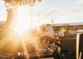 photo of music band performing at front of crowded stadium under blue sky